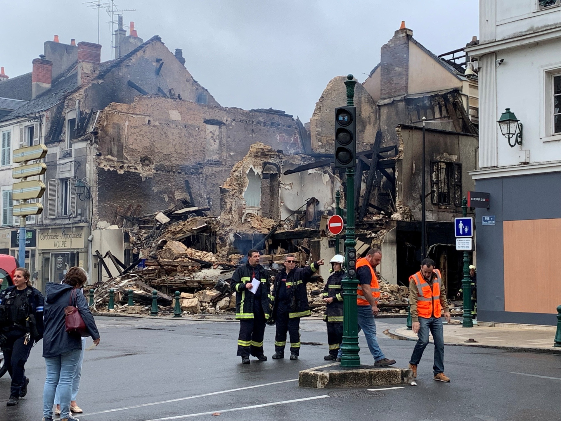 Emergency personnel survey the scene of a burnt out building - which housed a pharmacy - in Montargis, some 100kms south of Paris on July 1, 2023, which was set alight overnight during continuing protests following the shooting of a teenage driver in the suburb of Nanterre on June 27. Violence and looting hit France in a fourth night of protests as massively deployed police made nearly 1,000 arrests and the country braced for more riots ahead of the funeral of the teenager who was killed by an officer during a traffic stop. The government said the violence had "lessened" compared to previous nights, but the interior ministry still reported 994 arrests nationwide overnight, and 79 injuries among police and gendarmes. (Photo by Mathieu RABECHAULT / AFP) (Photo by MATHIEU RABECHAULT/AFP via Getty Images)