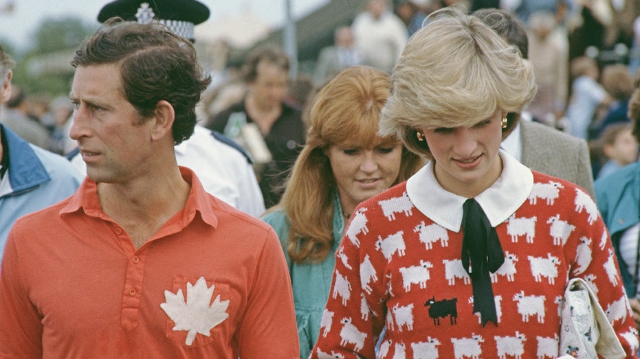 Princess Diana wearing her black sheep sweater walking alongside Prince Charles wearing a red polo shirt