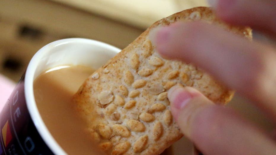 Hand dipping belVita biscuit into tea