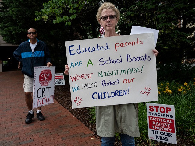 People hold up signs during a rally against "critical race theory" (CRT) being taught in schools at the Loudoun County Government center in Leesburg, Virginia on June 12, 2021. - "Are you ready to take back our schools?" Republican activist Patti Menders shouted at a rally opposing anti-racism teaching that critics like her say trains white children to see themselves as "oppressors." "Yes!", answered in unison the hundreds of demonstrators gathered this weekend near Washington to fight against "critical race theory," the latest battleground of America's ongoing culture wars. The term "critical race theory" defines a strand of thought that appeared in American law schools in the late 1970s and which looks at racism as a system, enabled by laws and institutions, rather than at the level of individual prejudices. But critics use it as a catch-all phrase that attacks teachers' efforts to confront dark episodes in American history, including slavery and segregation, as well as to tackle racist stereotypes. (Photo by ANDREW CABALLERO-REYNOLDS / AFP) (Photo by ANDREW CABALLERO-REYNOLDS/AFP via Getty Images)