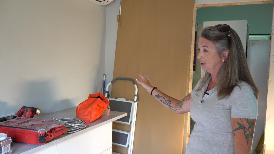 A woman points to a counter with construction tools on top in a home under construction