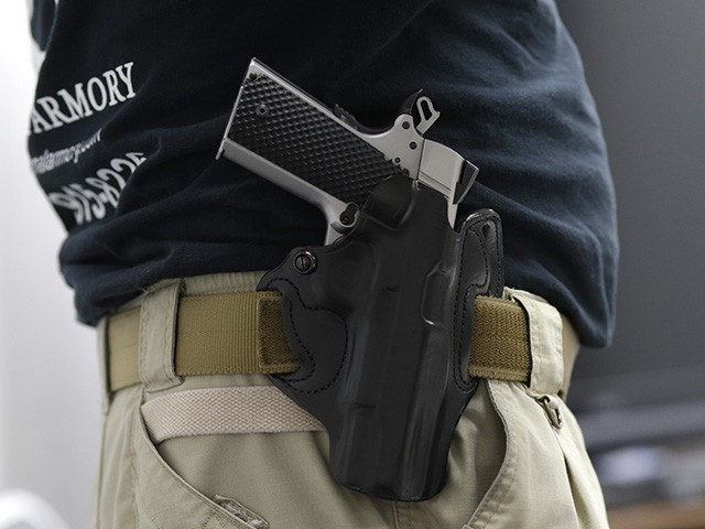 FILE - In this Jan. 5, 2016 file photo, Mike Weinstein, director of training and security at the National Armory gun store and gun range, wears a Ruger 1911 handgun in a holster as he teaches a concealed weapons permit class in Pompano Beach, Fla. Florida might grant authority to 2 million civilians who can lawfully carry guns tucked in waistbands, under jackets or inside purses into restaurants, shopping malls and elsewhere. (AP Photo/Lynne Sladky, File)