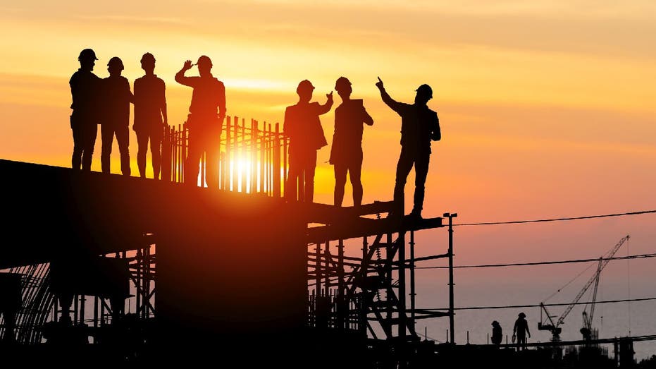 laborers stand on industrial site