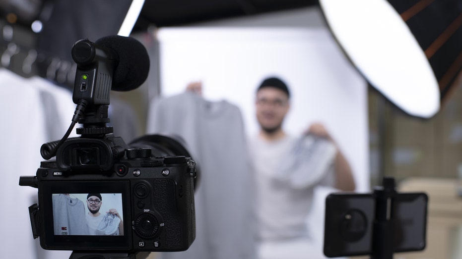 Man films himself showing off a shirt and sneakers.