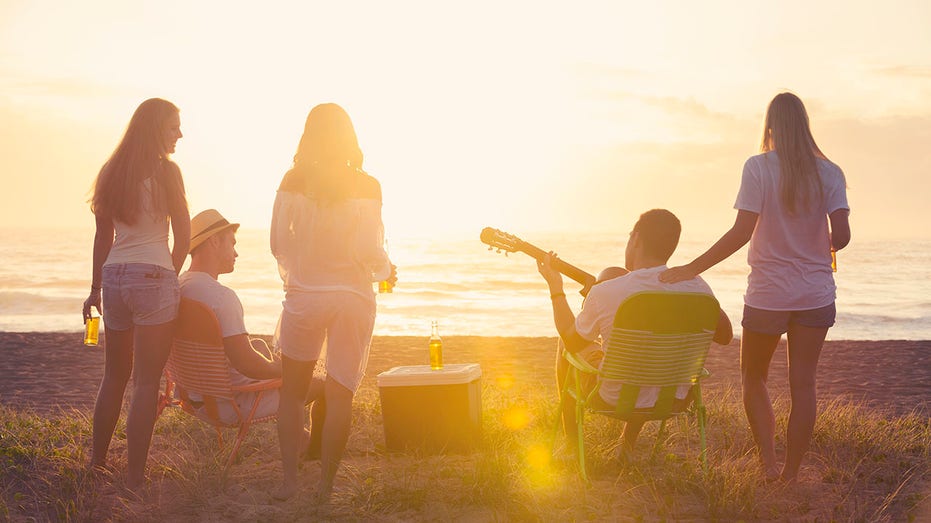 Relaxed friends beach party at sunset with 5 people.