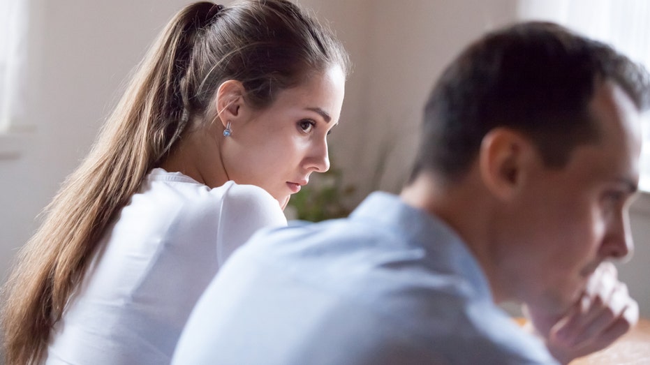 Woman sneaks a sidelong glance at a distressed man.