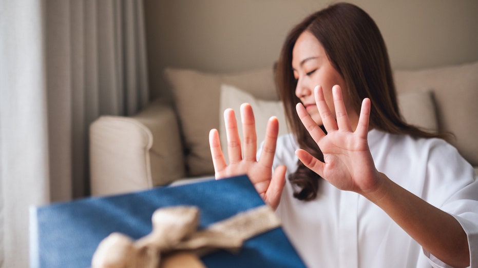 Woman rejects a proffered blue gift box.