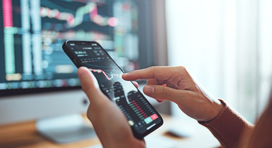 Close-up view a person's hands going over stocks on a smartphone.