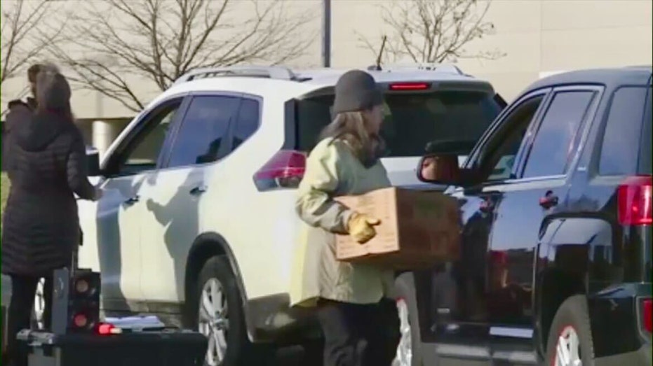 People are seen distributing food at a food giveaway