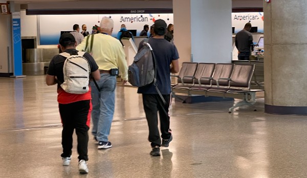 An NGO staffer escorts migrants through the Tucson International Airport to a special TSA screening line. (Randy Clark/Breitbart Texas)