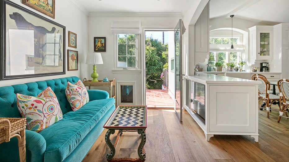 A green couch in a room with the door open