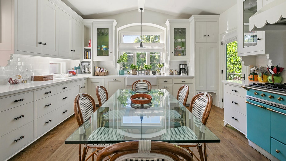 An all white kitchen with a blue stove.