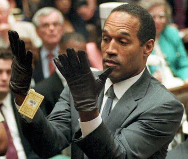 Los Angeles, UNITED STATES: : This 21 June 1995 file photo shows former US football player and actor O.J. Simpson looking at a new pair of Aris...